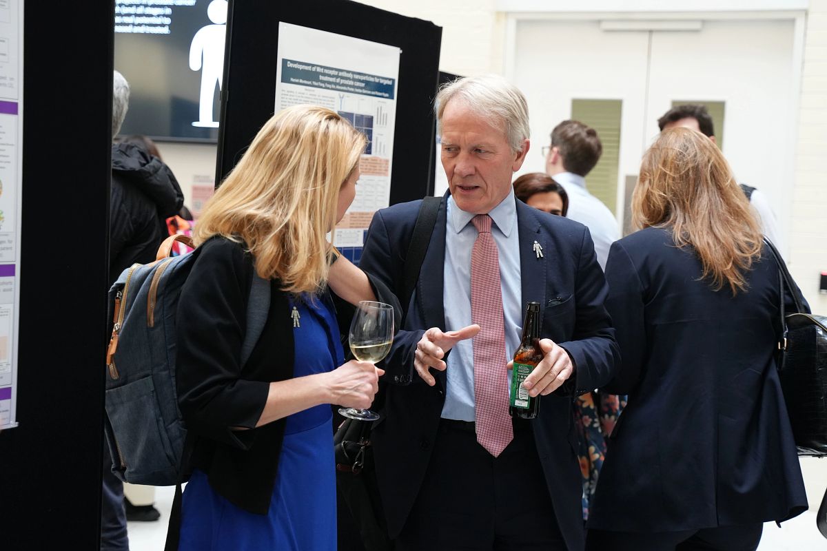 A man and a woman at an event having a conversation in front of some presentation displays