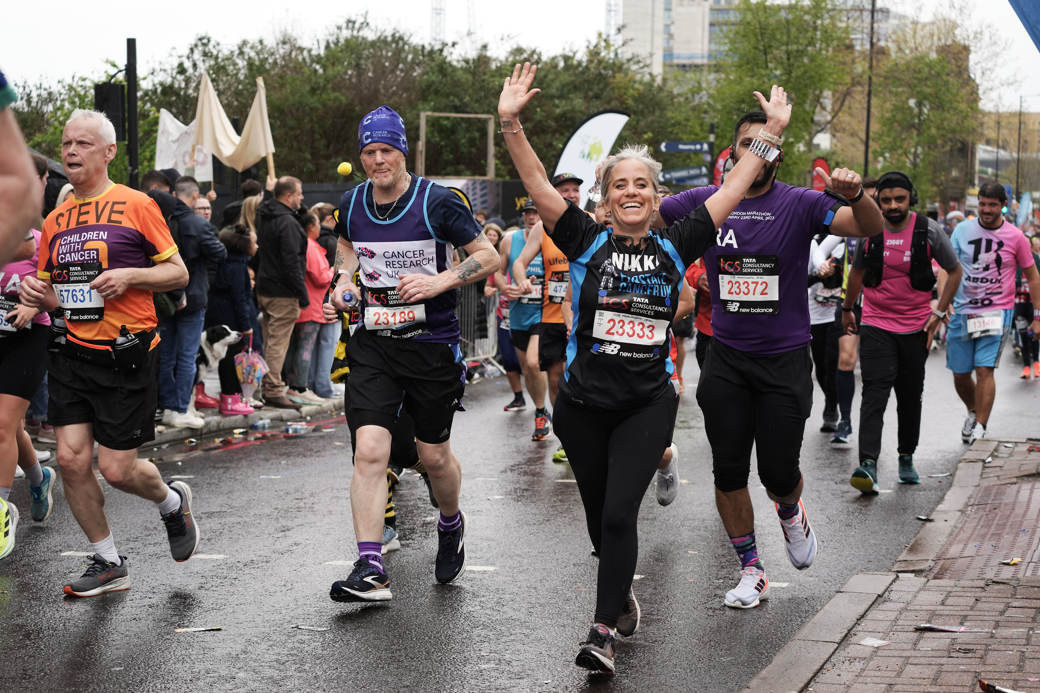 A woman raising her hands in the air and smiling while taking part in a fundraising run for Prostate Cancer UK.