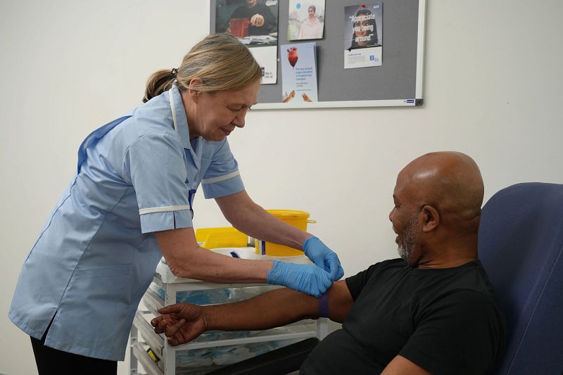 A nurse taking a blood sample from a man for prostate cancer treatment tests