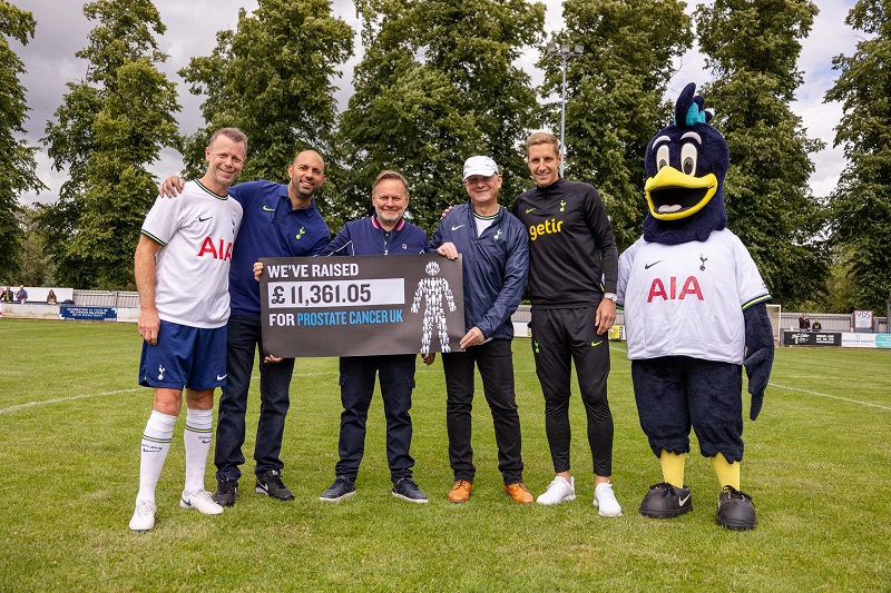 A group of men standing on a football pitch showing that they've raised £11,361.05 for Prostate Cancer UK.
