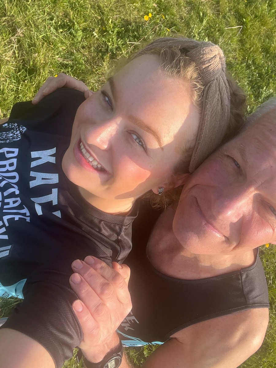 A man and a young woman wearing black Prostate Cancer UK running kit posing for a selfie.