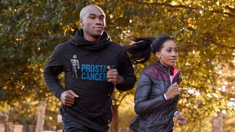 A man and a woman running together, wearing Prostate Cancer UK running tops