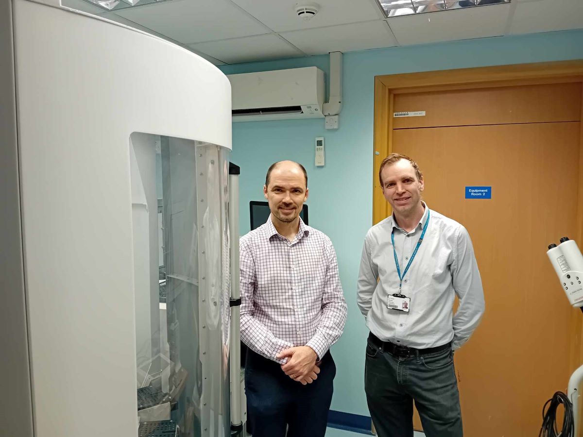 Professor Ferdia Gallagher with collaborator Tristan Barrett, stood next to a hyperpolariser machine used to conduct innovative metabolic MRI imaging