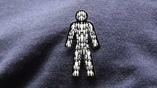 A black and white Man of Men logo badge on a blue jumper. 