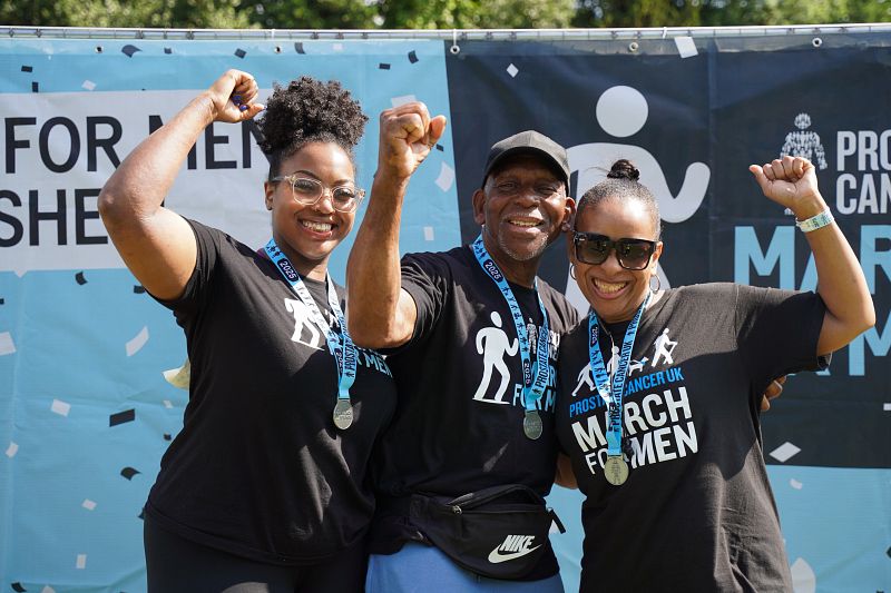 A man and two women punch the air in celebration after completing a fundraising walk.