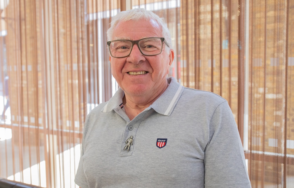 Allan Roper wearing glasses, a grey tee-shirt and the Prostate Cancer UK 'Man of Men' badge