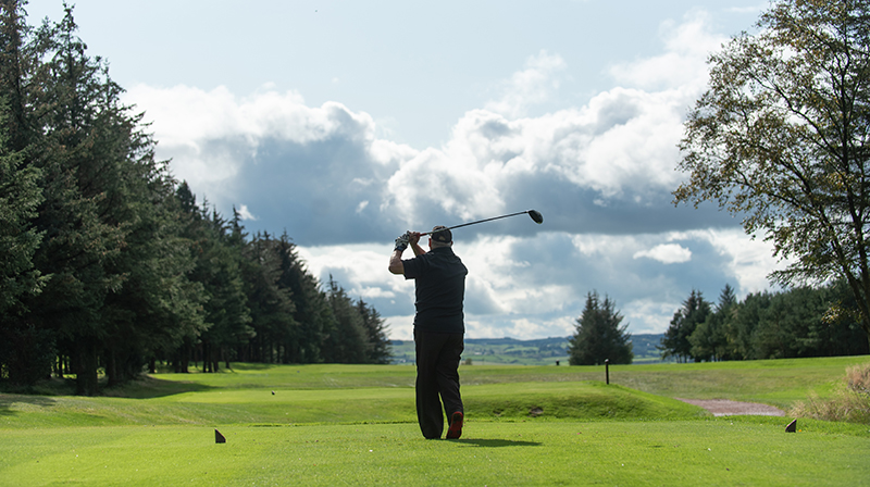 A man standing on a golf course swinging his golf club