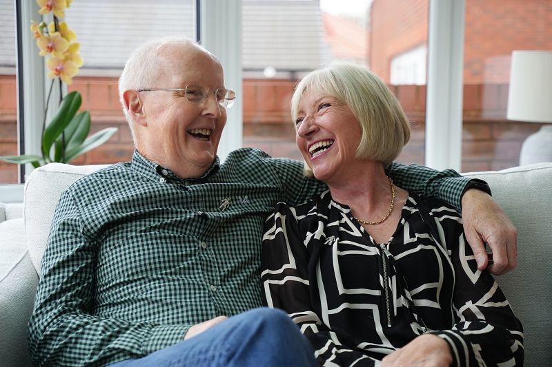 A man and woman sitting on a sofa, smiling at each other