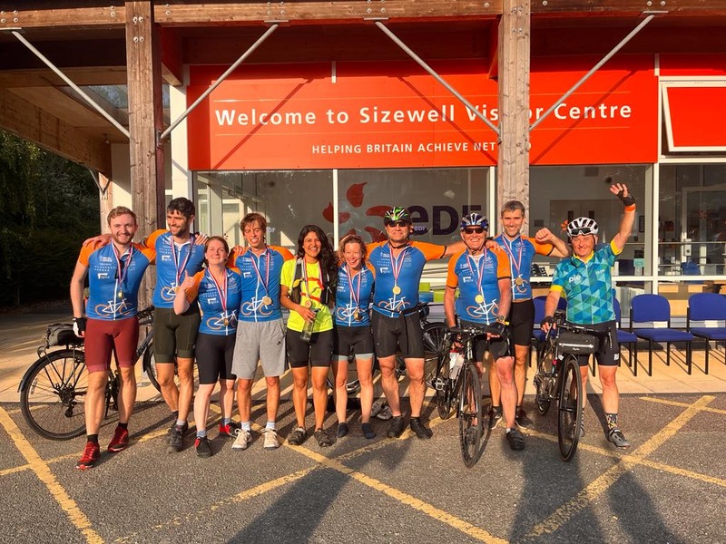 A large group of cyclists in matching blue uniforms gather together for a fundraising bike ride.