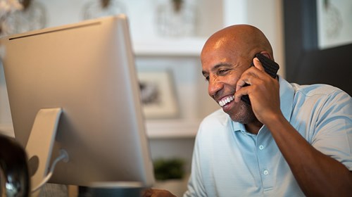 A man smiling while holding a mobile phone to his ear.