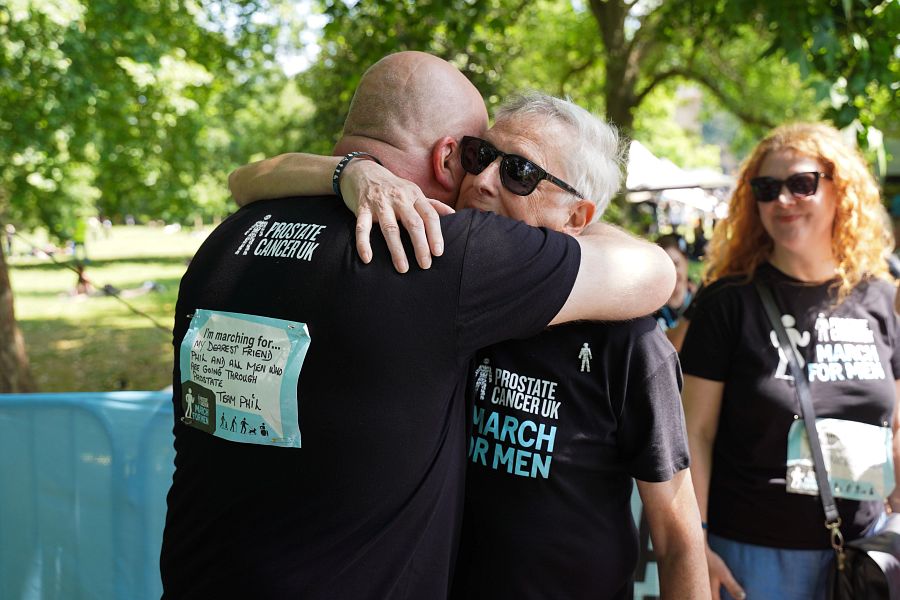 Two men wearing black Prostate Cancer UK t-shirts share a hug after completing the March for Men event.