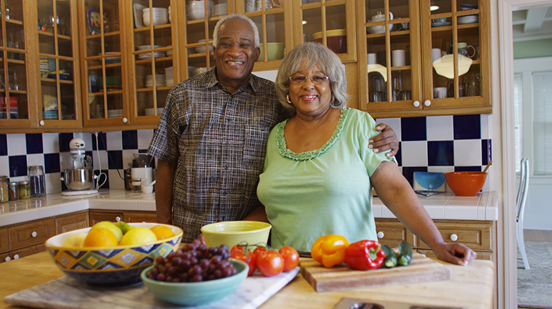 A husband and wife chopping vegetables.