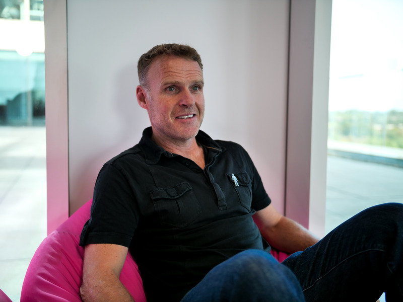 A man wearing a black polo shirt, sitting on a pin bean bag chair.