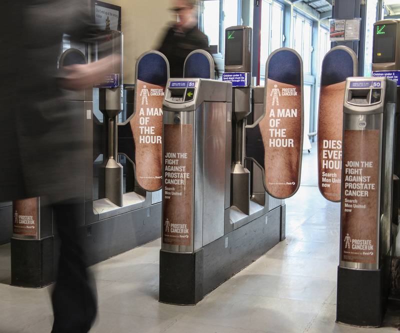Ticket barrier gates at a London Underground station that feature branding from a prostate cancer awareness campaign.