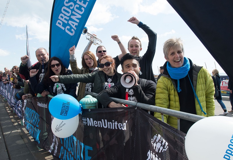 Prostate Cancer UK supporters cheer on runners at a marathon event.