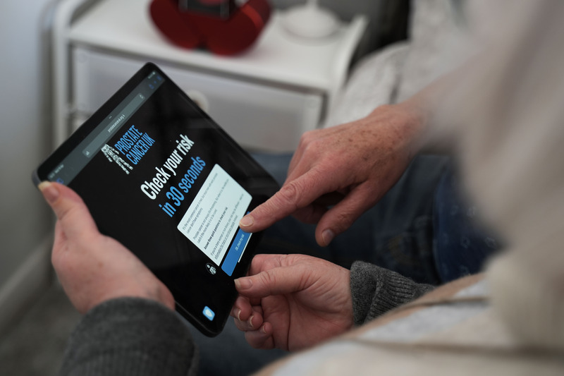 A close-up image of a man and a woman using a tablet device to take the Prostate Cancer UK online Risk Checker.