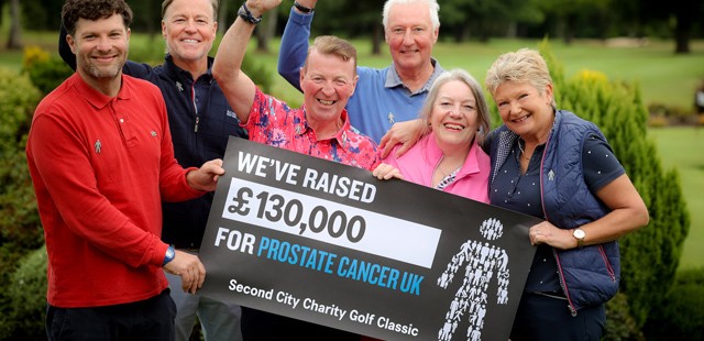 A group of people smiling while showing that they've raised £130,000 for Prostate Cancer UK.