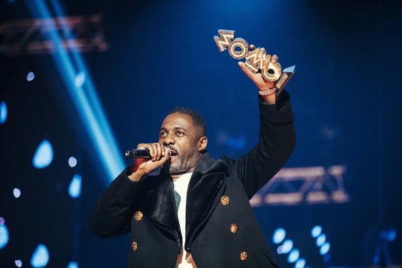 Actor Idris Elba raises a MOBO award in the air while speaking into a microphone at the ceremony in 2017