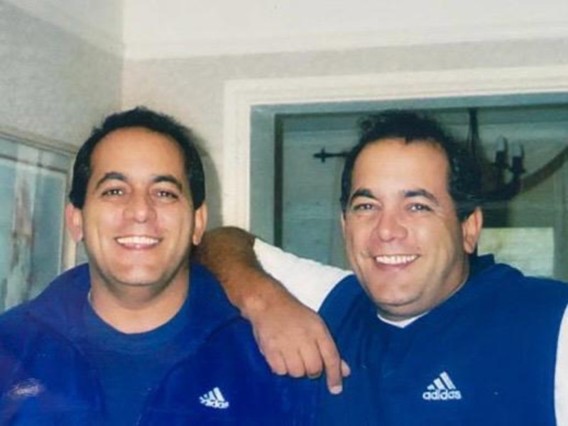 An older photo of Dave and Pete Cossie in their younger years, smiling and laughing together wearing football kit