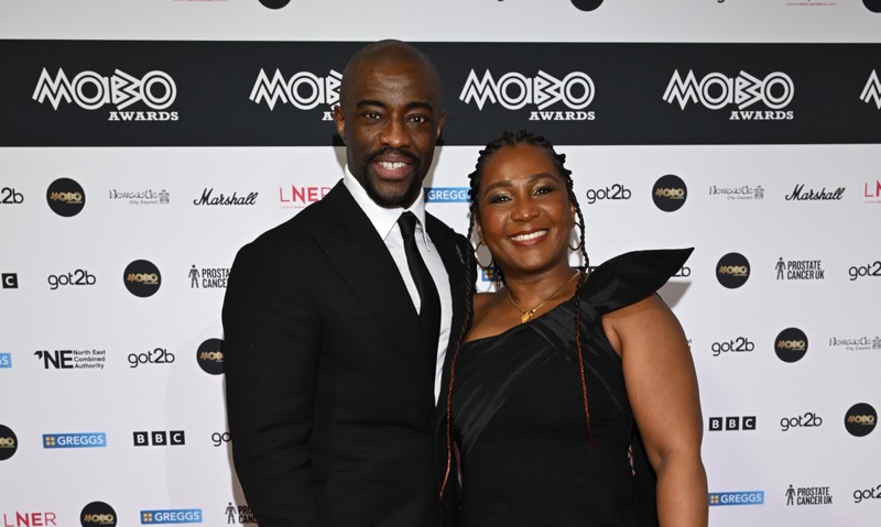 A man wearing a black suit and tie and a woman wearing a black dress