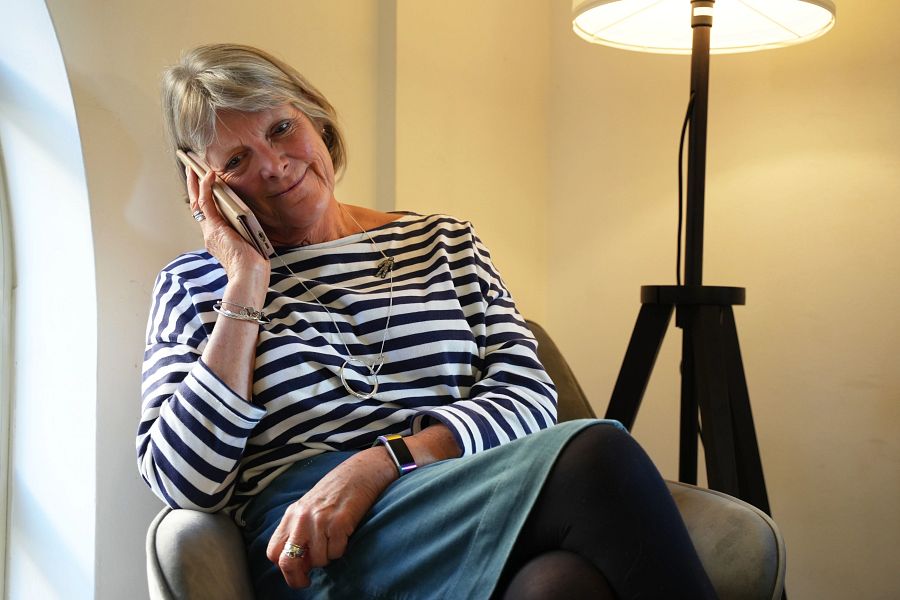 A woman wearing a stripy shirt sitting on a chair and holding a mobile phone to her ear
