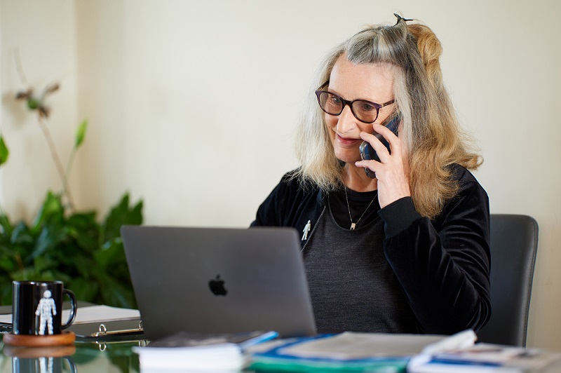 A One-to-One Peer Support Service volunteer smiling while talking on the phone. 