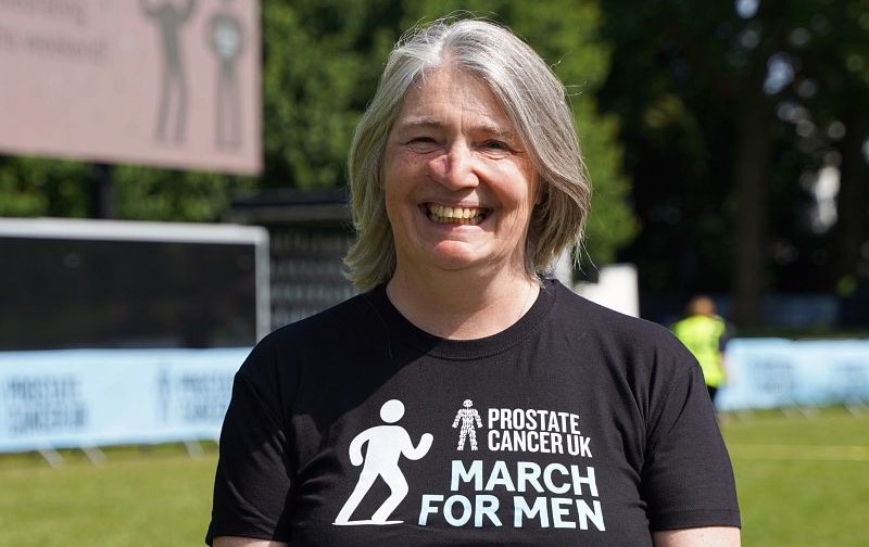 A woman smiling and wearing a black Prostate Cancer UK branded t-shirt
