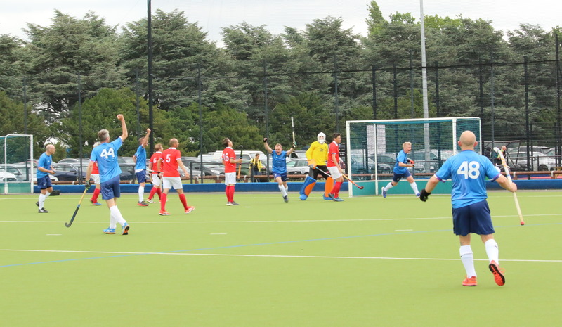 A hockey player wearing a blue shirt celebrates with team mates after scoring a goal.