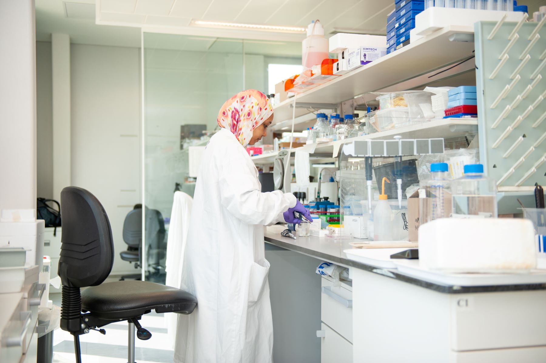 Women wearing white lab coat standing at a lab desk doing research