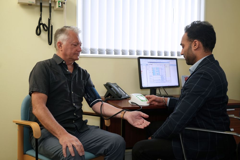 A doctor checks a man's blood pressure in a GP surgery